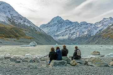 a family sits on the banks of Hooker Lake, New Zealand