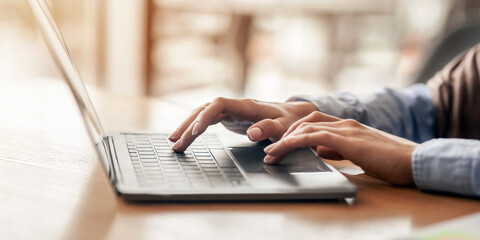 Female hands typing on laptop over blurred background, side view, freelance concept, cropped, empty...