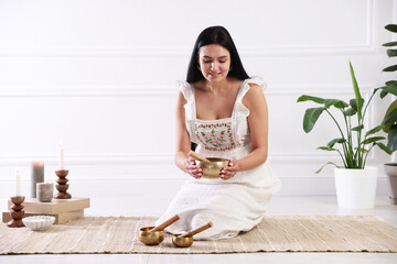 Woman with singing bowls on floor indoors