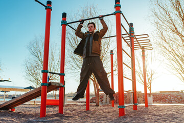 Man doing pull-ups on the street on spring day