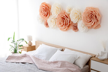 Beautiful decorative paper flowers on wall in bedroom