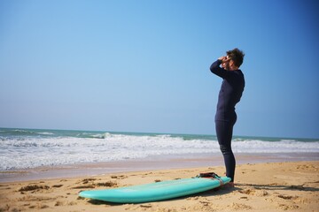 Surfer in Wetsuit Watching Ocean Waves