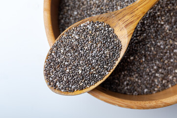 Chia seeds in wooden spoon on white background. Close up.