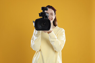 Obraz premium Happy woman with professional video camera on orange background