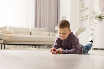Fototapeta premium Little boy playing with toy car at home. Space for text