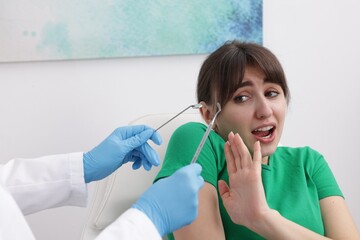 Scared woman refusing dentist's examining in clinic