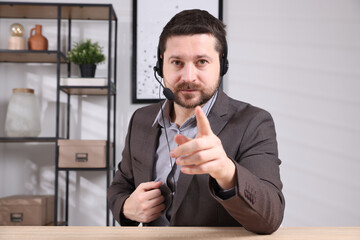 Online speaker in headset streaming webinar at table indoors, view from web camera