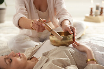 Woman undergoing singing bowl therapy indoors, closeup