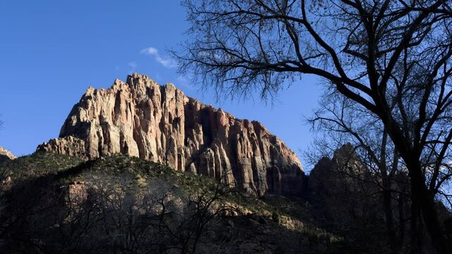Golden sunlight illuminates the towering cliffs of Zion National Park during sunset, highlighting the natural beauty of the rugged landscape in Utah's wilderness.