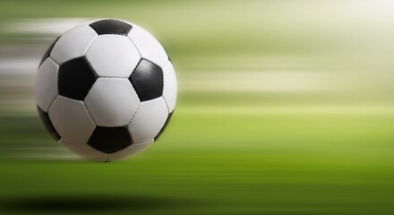 Fototapeta premium Soccer ball in motion on green field background with copy space. Sport equipment for World Cup, Champions League. Concept for football match, game day, betting