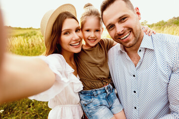 Family Portrait. Closeup of adorable couple with cute kid taking selfie, having fun outdoors