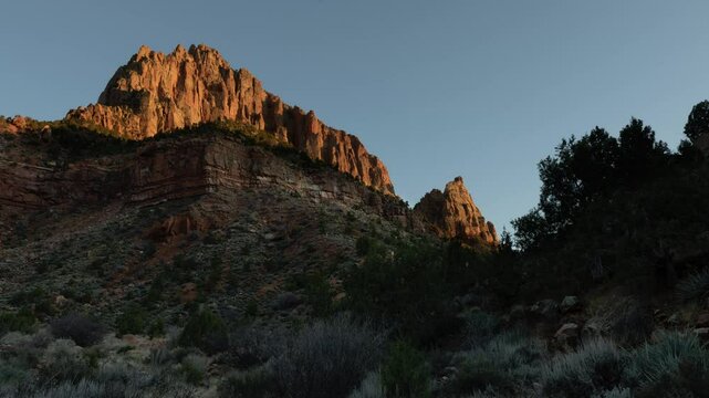 As the sun sets, warm hues bathe the towering cliffs of Zion National Park in Utah, creating a breathtaking display of color and light.
