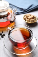Aromatic black tea and sugar cubes on light table, closeup