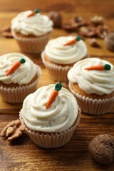 Delicious carrot cupcakes and walnuts on wooden table, closeup