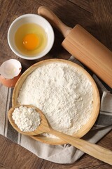 Rolling pin, flour and yolk on wooden table, flat lay