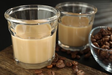 Coffee cream liqueur in glasses and beans on table, closeup