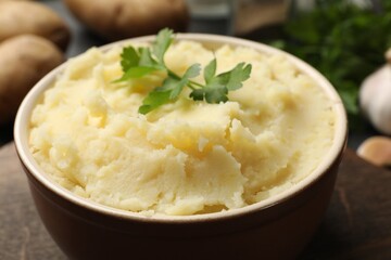 Delicious mashed potato with parsley in bowl on table, closeup