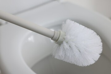 Cleaning toilet bowl with white brush, closeup