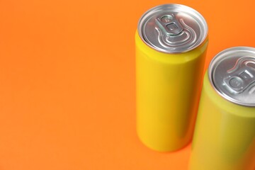 Two tin cans on orange background, closeup. Space for text