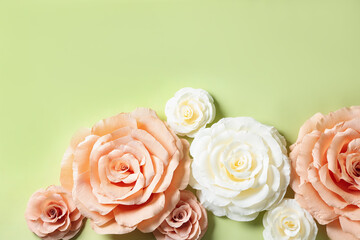 Beautiful paper flowers on light green background, flat lay. Space for text
