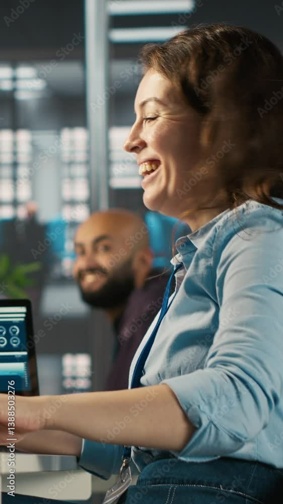 Poster vertical video cheerful employee at office desk having fun with coworkers while editing documents on