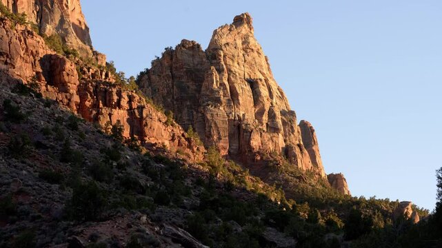 As the sun sets, warm hues bathe the towering cliffs of Zion National Park in Utah, creating a breathtaking display of color and light.