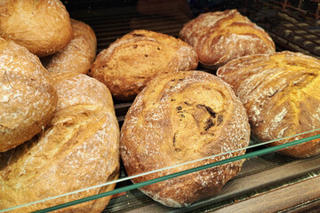Fresh rustic bread in bakery. Golden crust loaves on display. Artisan style baked goods. Traditional bread with flour dust. Crispy surface close up. Natural homemade food presentation.