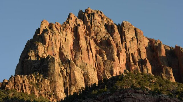 As the sun sets, warm hues bathe the towering cliffs of Zion National Park in Utah, creating a breathtaking display of color and light.