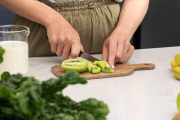 Preparing fresh kiwi slices for a healthy smoothie in a modern kitchen setting
