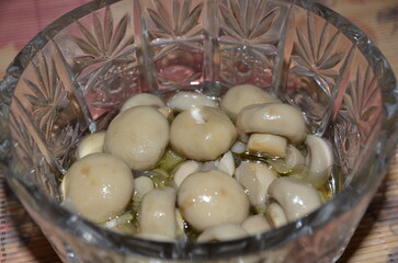 Marinated small champignon mushrooms in a crystal vase.