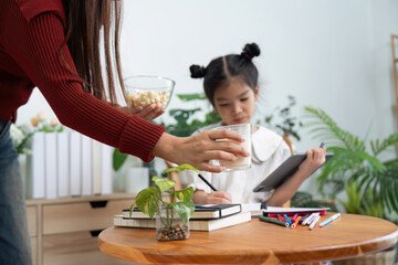 Learning and Nurturing. A mother attends to her daughter while she works on her school tasks.