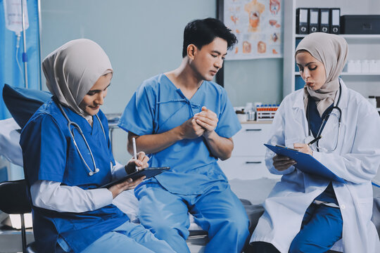 A young man lies on a bed in a hospital ward talking with her young Indian doctor. Doctor checking patient's health doctor treating patient, hospital admission of patient