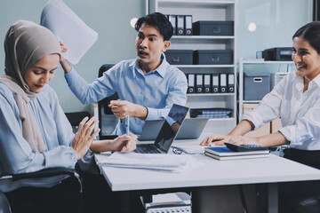 Young asian businesswoman suffering from headache while colleagues arguing and blaming her for bad...
