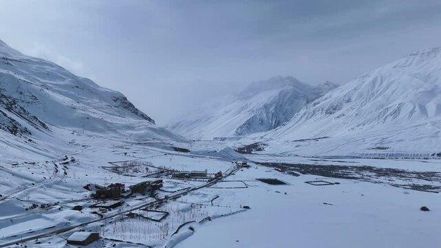 Aerial drone shot showcasing the serene beauty of Kaza blanketed in fresh white snow, with its traditional houses, monasteries, and winding roads visible from above.