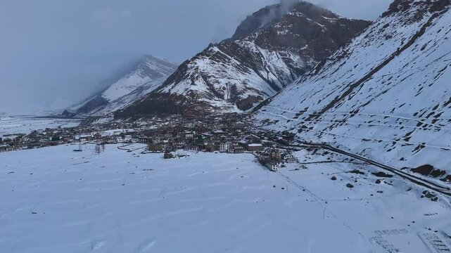 Aerial drone shot offering a mesmerizing panoramic view of snow-covered Kaza, where the vast white landscape stretches endlessly, blending into the dramatic mountain skyline.