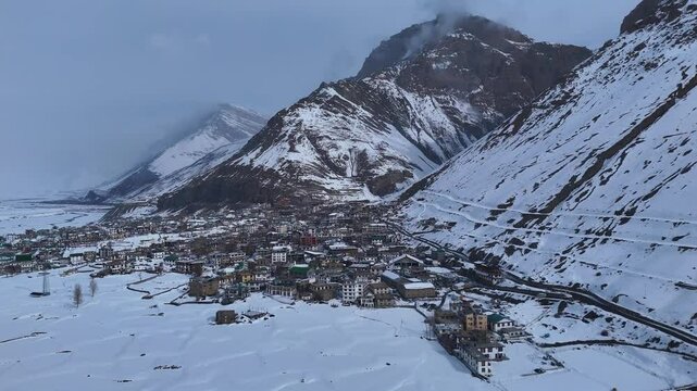 Aerial drone shot featuring the frozen beauty of Kaza, with its ancient monasteries and traditional homes wrapped in snow, standing resilient against the harsh winter.