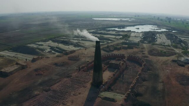 Aerial view of a brick factory emitting smoke from its chimney, showcasing the brick making process and environmental impact near Sukkur, Sindh
