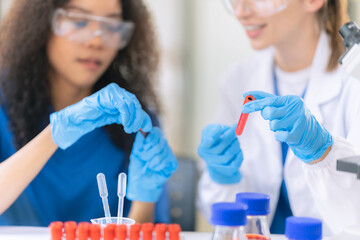 Two female scientists examine liquids in test tubes in a modern laboratory, handling chemicals and...