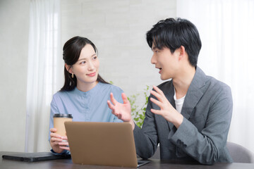オフィスで女性の先輩上司に相談や企画や提案ををし会話する新人の男性社員の男女ビジネスイメージ