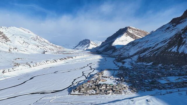 Aerial drone shot capturing the stunning view of Kaza city blanketed in snow, with golden sunlight casting a warm glow over the winter landscape.