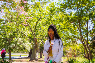 Naklejka premium An African American woman holding a flower at the Los Angeles County Arboretum and Botanic Garden in Arcadia California USA