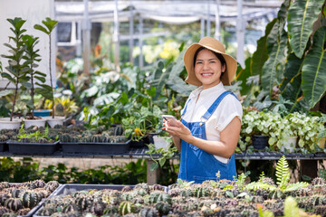 Obraz premium Happy female gardener in green house with mobile augmented reality