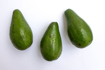 Three unripe avocado fruits on white background.