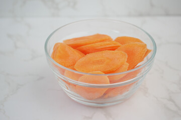 Freshly sliced carrots in a glass bowl on a kitchen countertop