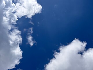 Obraz premium Beautiful blue sky with white clouds. The sky was clear and bright, and clouds were scattered all over the sky. The scene was peaceful and serene, as if the viewer was gazing at a beautiful day.