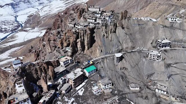 Aerial drone shot featuring Dhankar Monastery glowing under the golden hues of the setting sun, with snow-covered peaks forming a spectacular backdrop.