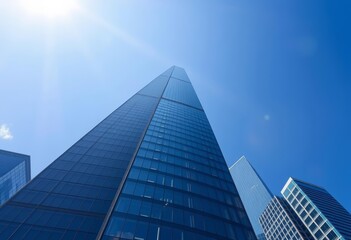 Fototapeta premium Sleek skyscraper ascends into a brilliant blue sky, blue sky, futuristic