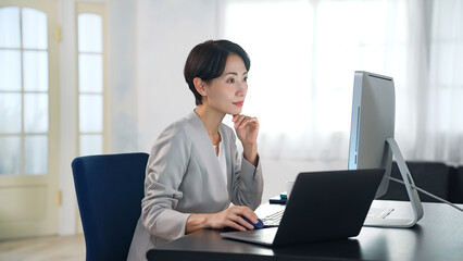 暗いオフィスでパソコンを使って作業する女性ビジネスパーソン