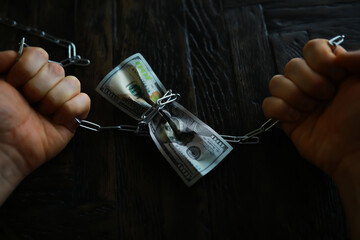 Handcuffed Hands Holding Dollars Symbolizing Financial Constraint on Dark Wood Background