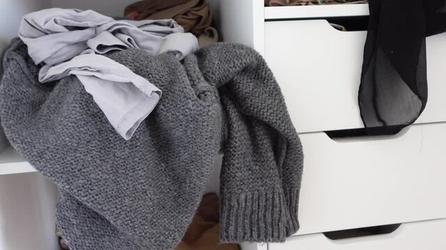Clothes overflowing from dresser drawers in messy bedroom space